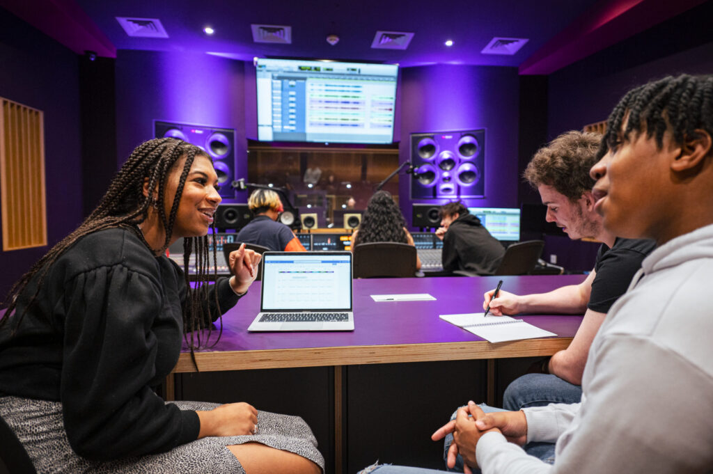 Students discussing music-related projects in a music studio