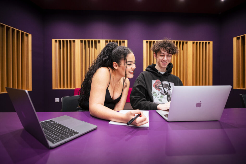 Students discussing music-related projects in a music studio
