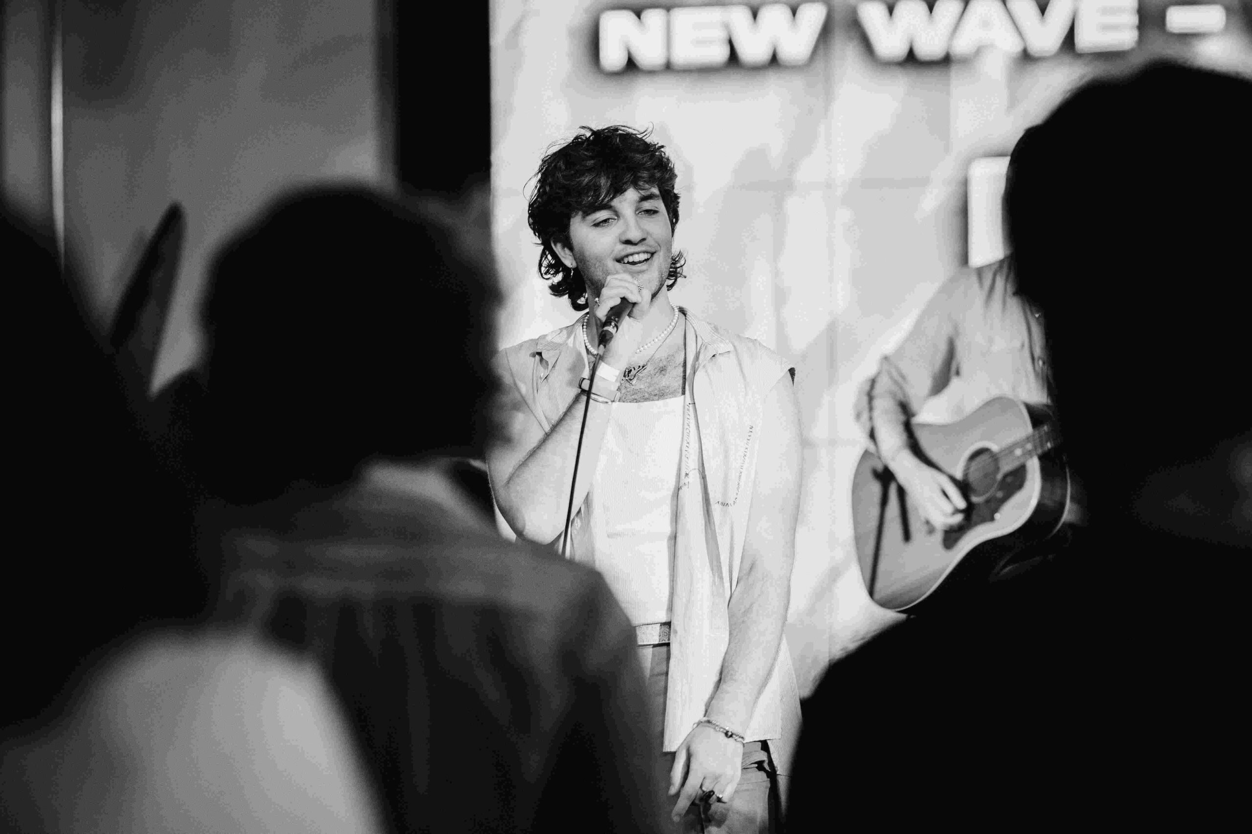 Person singing into a microphone with crowd watching.