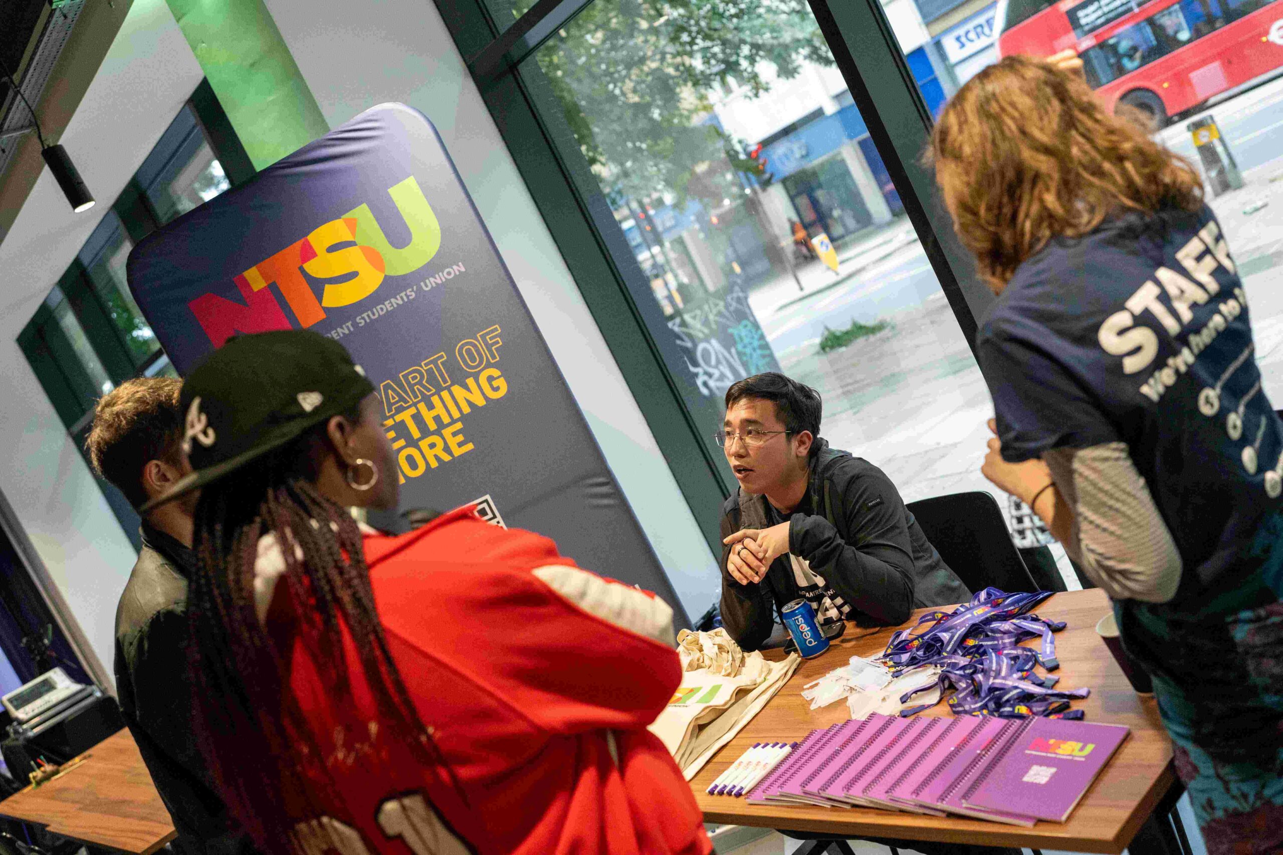 Students talking to someone sat at a table