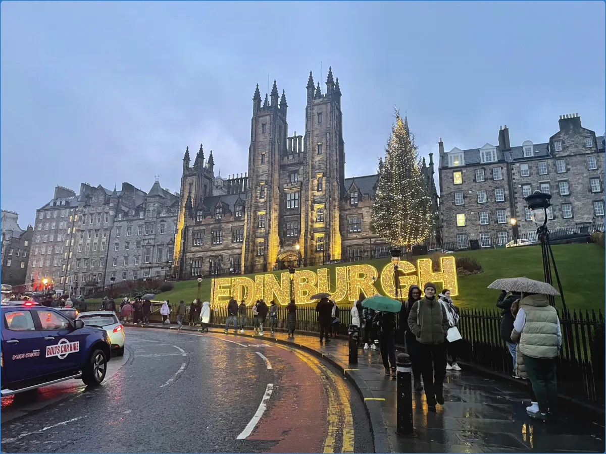 Edinburgh street with illuminated sign and Christmas tree.