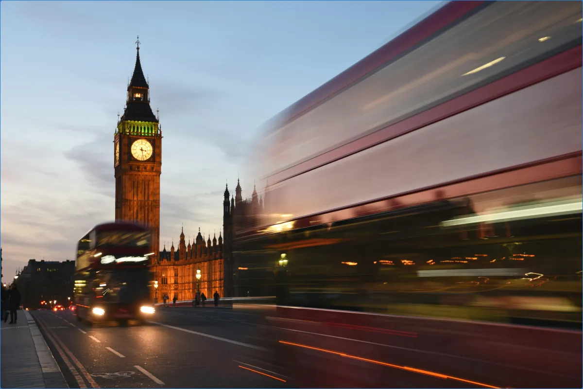 Big Ben and blurred double-decker buses at dusk