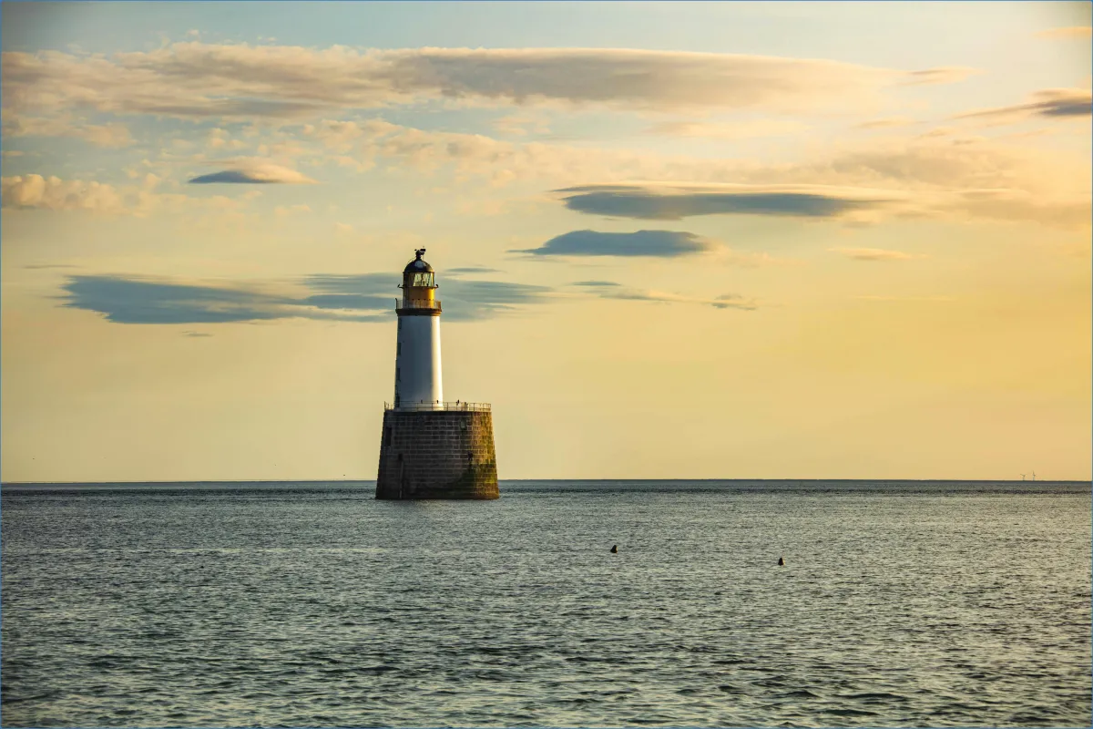 Lighthouse in calm sea at sunset