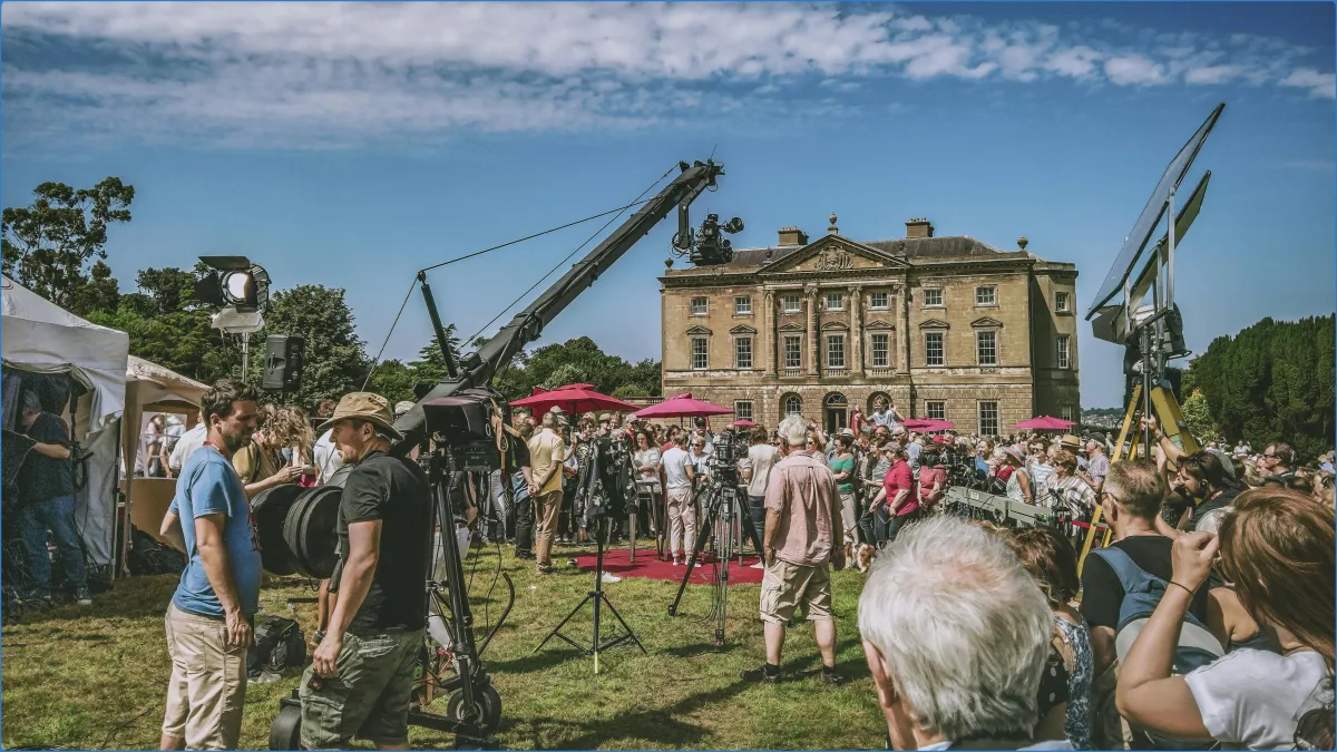 Film crew and crowd in front of a historic building.