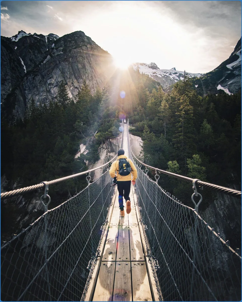 Person walking on a suspension bridge in the mountains