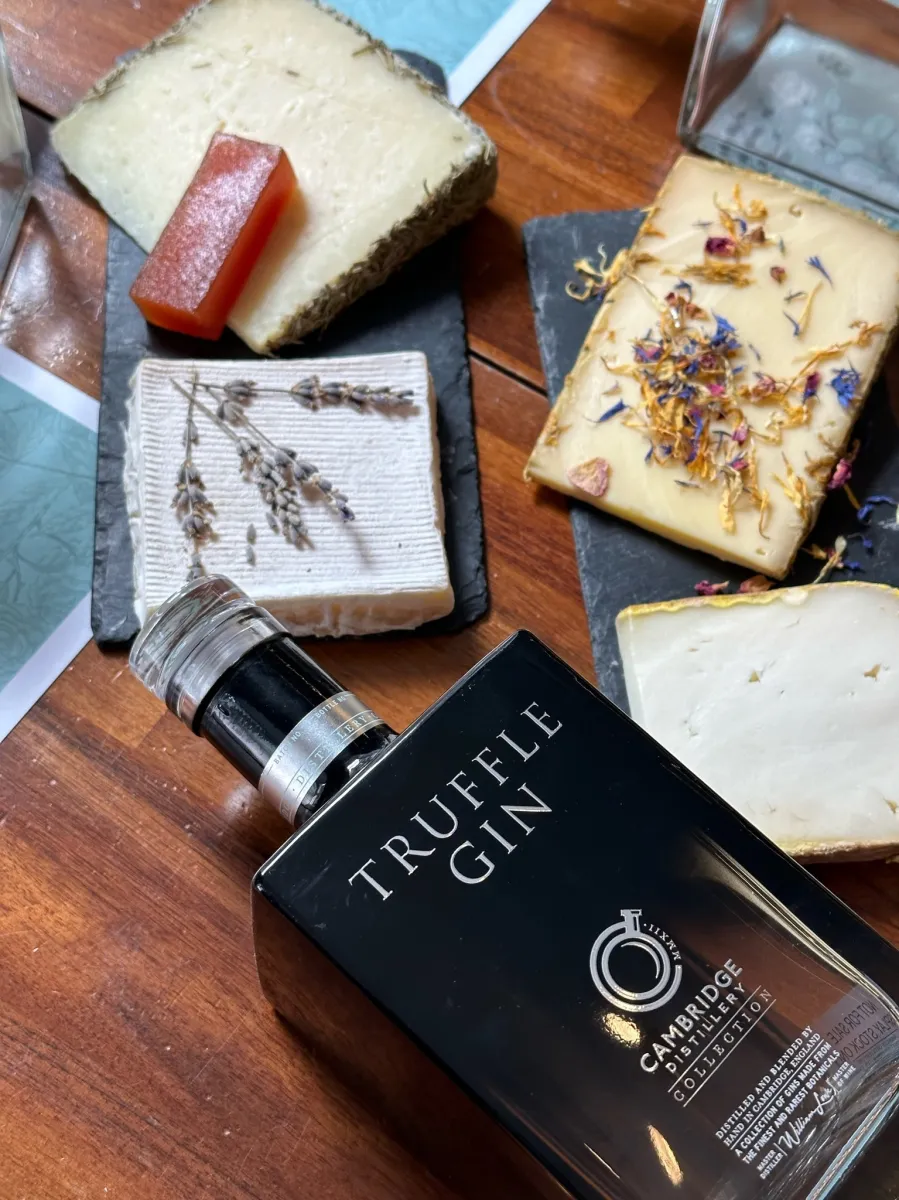 Truffle gin bottle with assorted cheeses on slate boards.