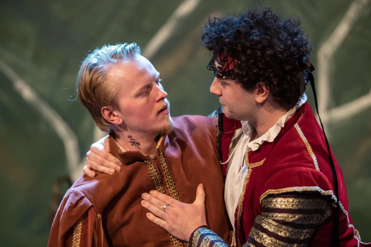 Two actors in period costumes performing on stage.