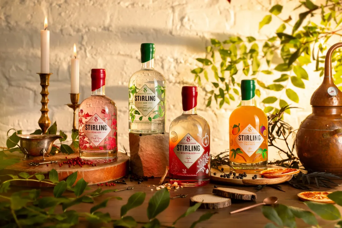 Four Stirling gin bottles with candles and leaves.