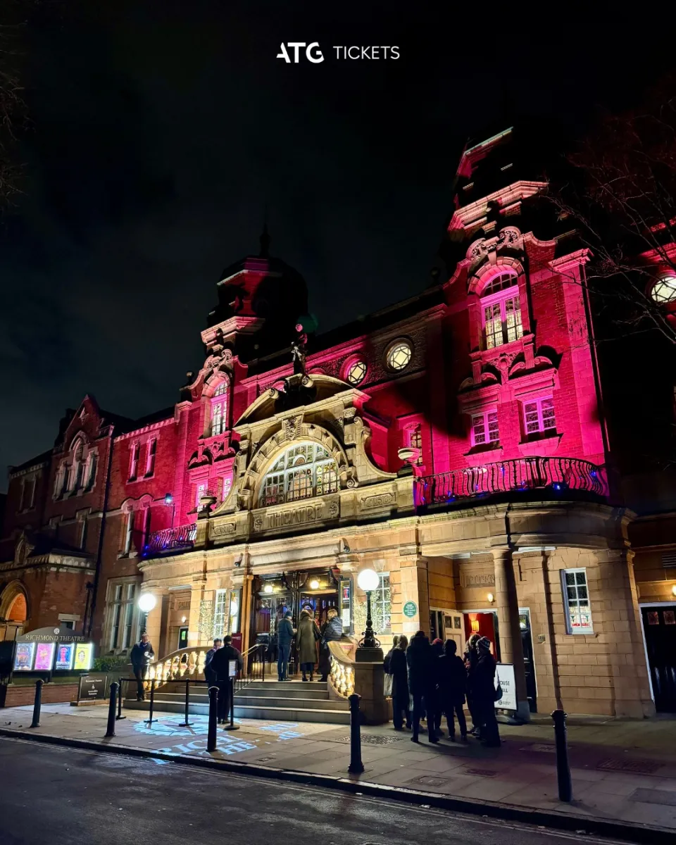 Illuminated theater entrance with people outside at night.
