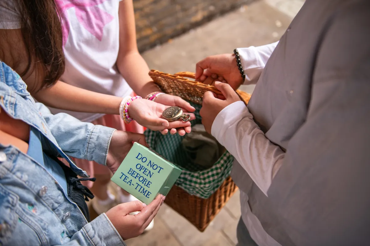 Hands holding a compass and a box labeled 'Do not open before tea-time'.