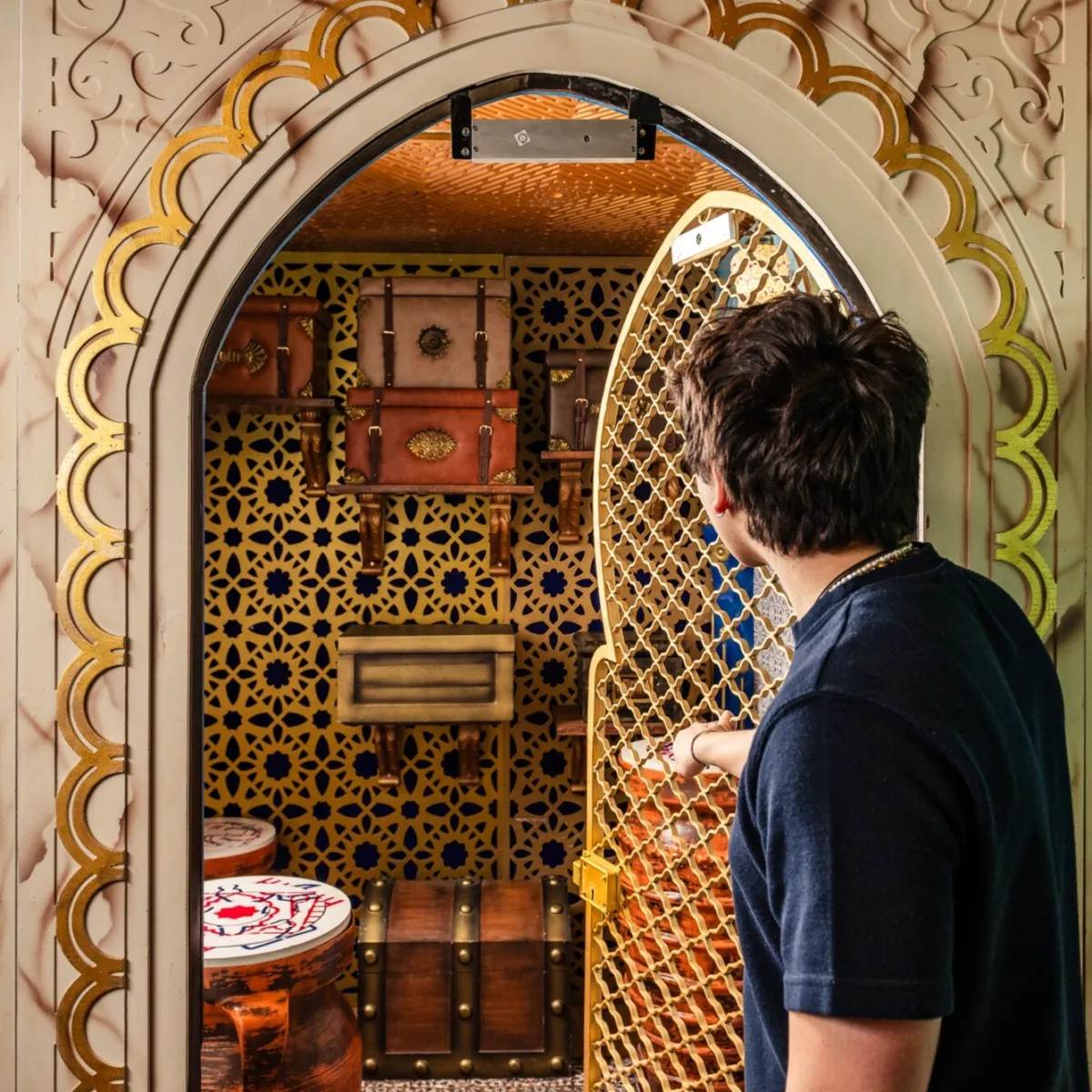 Person opening ornate door to a room with decorative items.