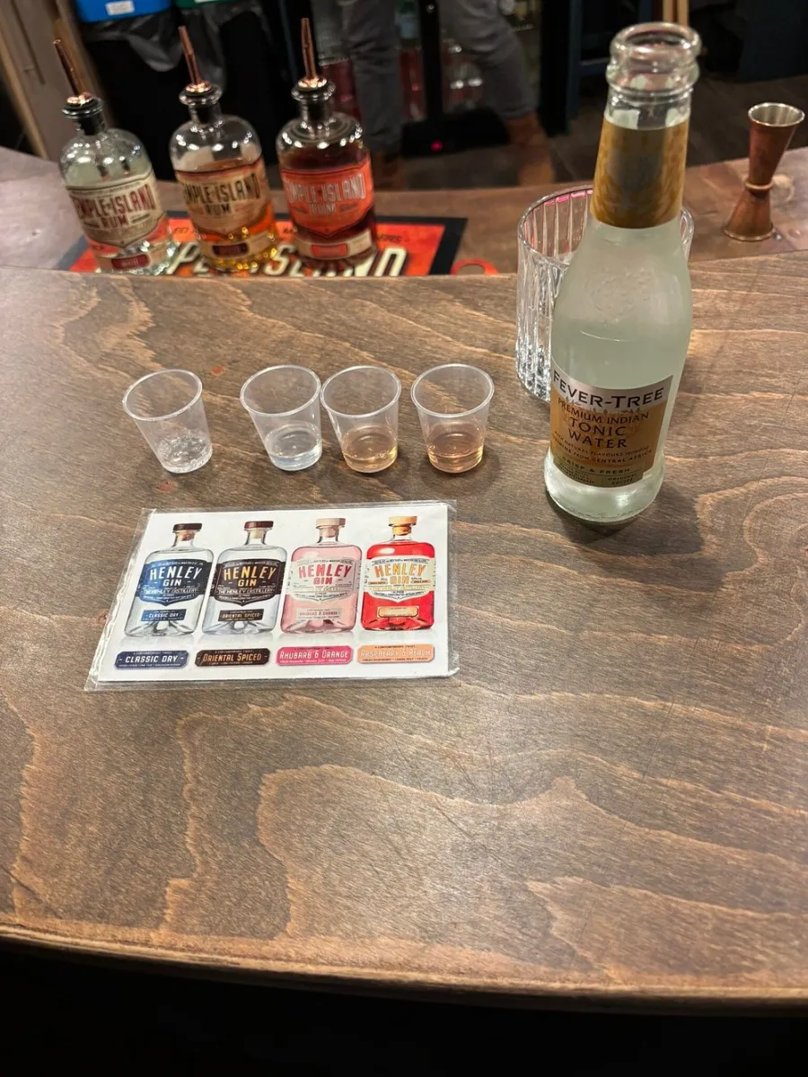 Bottles of rum, tonic water, and tasting cups on a bar counter.
