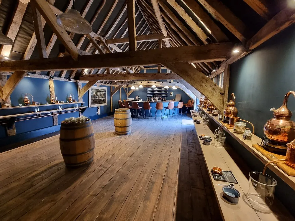 Rustic room with barrels and copper distillery equipment.