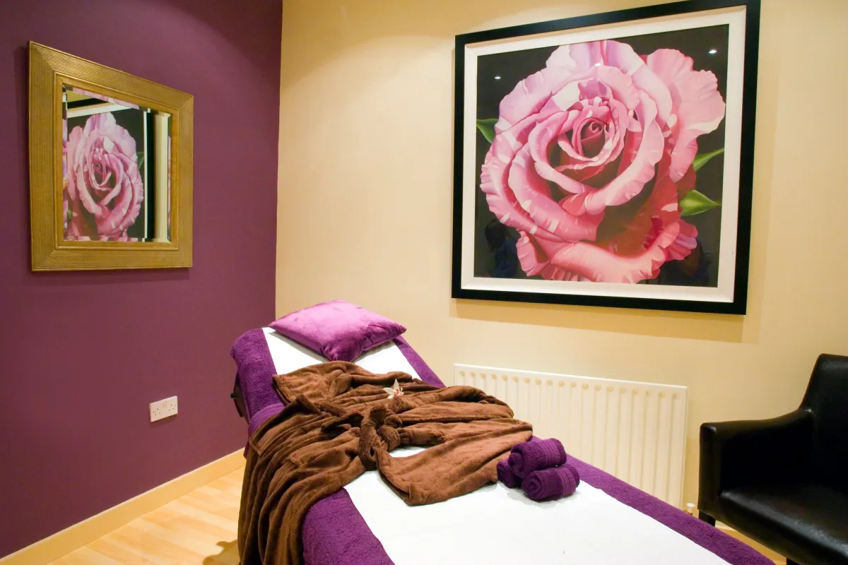 Massage room with a bed and floral artwork.
