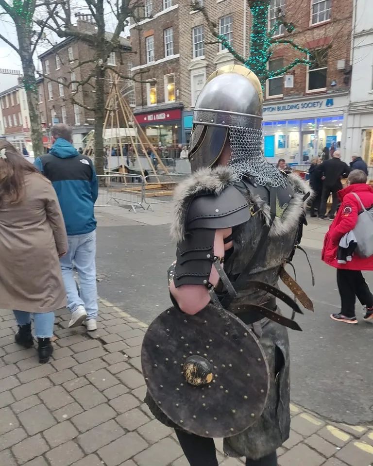 Person in medieval armor walking on a street.