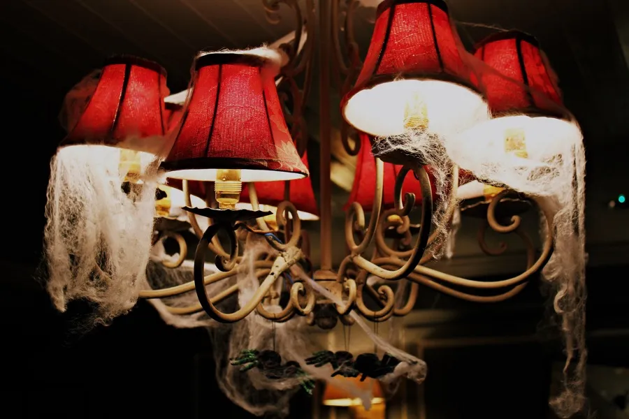 Chandelier with red lampshades and cobwebs.