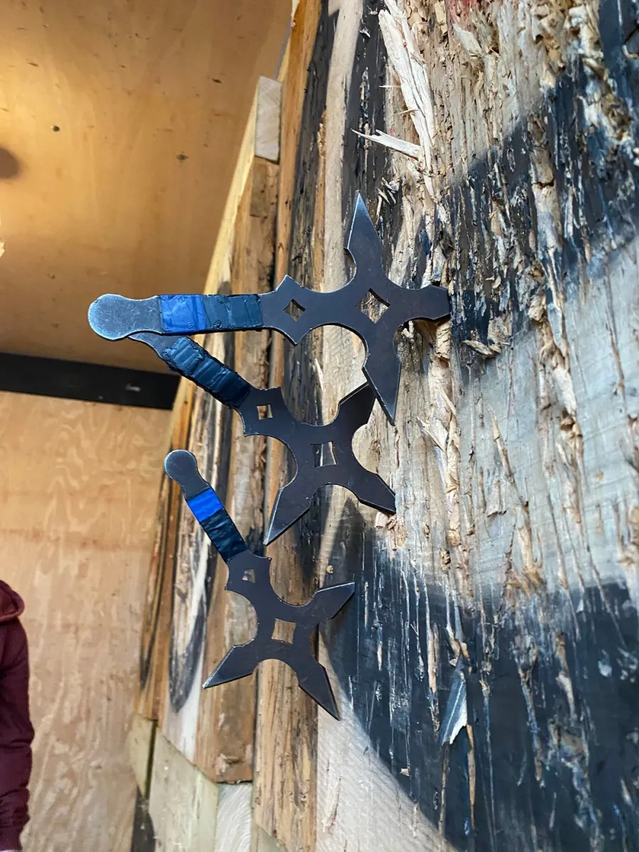 Three throwing stars stuck in a wooden target.