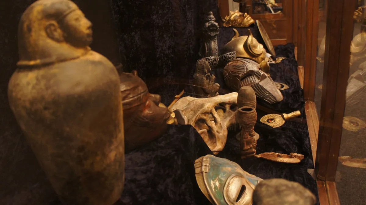 Collection of ancient masks and artifacts in a display case.