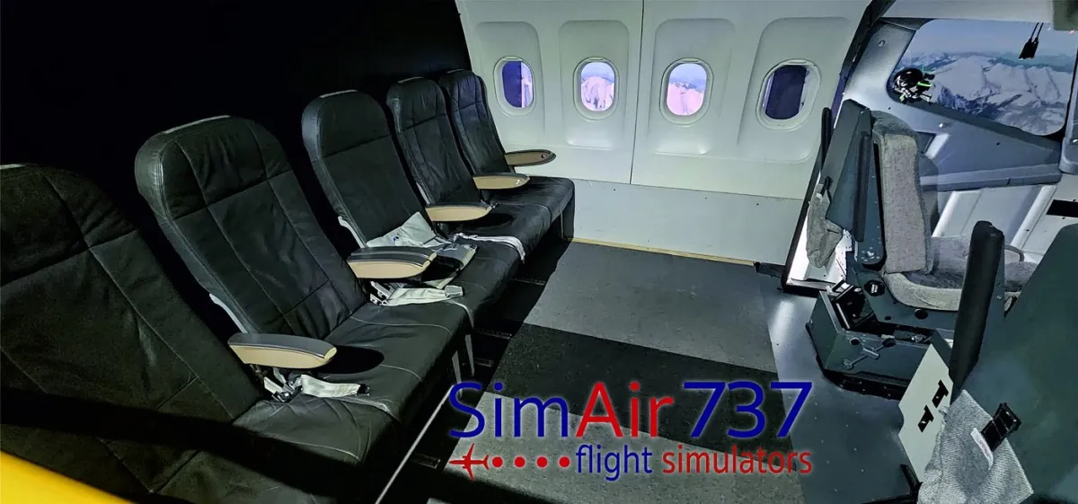 Interior of a flight simulator with passenger seats and cockpit.