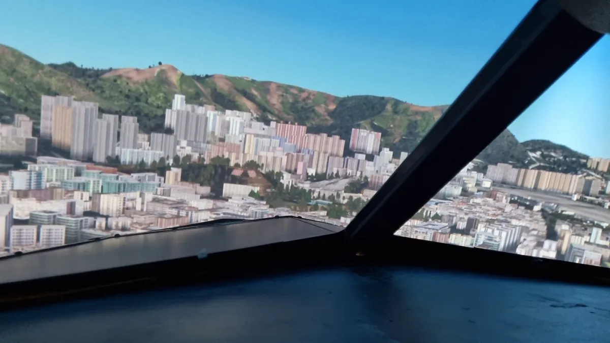 View of cityscape and mountains from cockpit window.