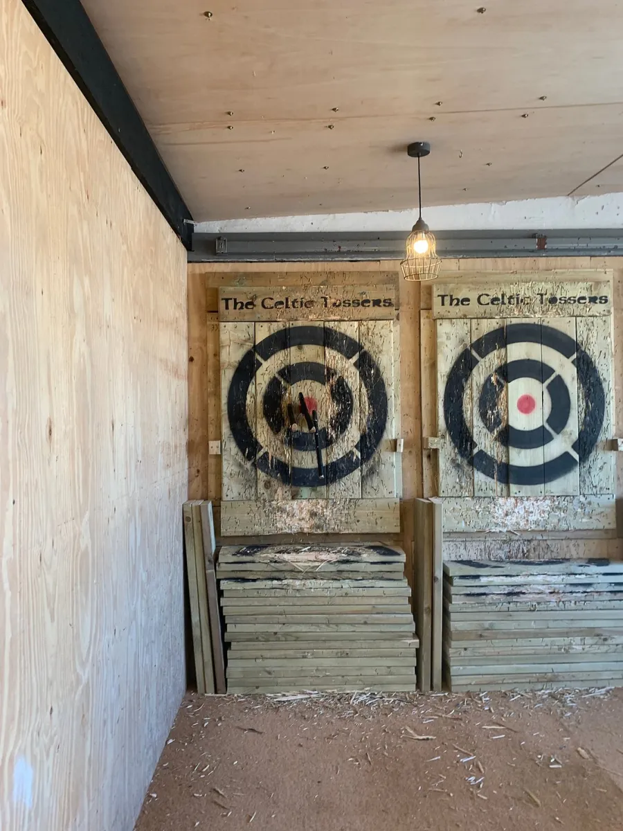 Indoor axe throwing targets with axes embedded.