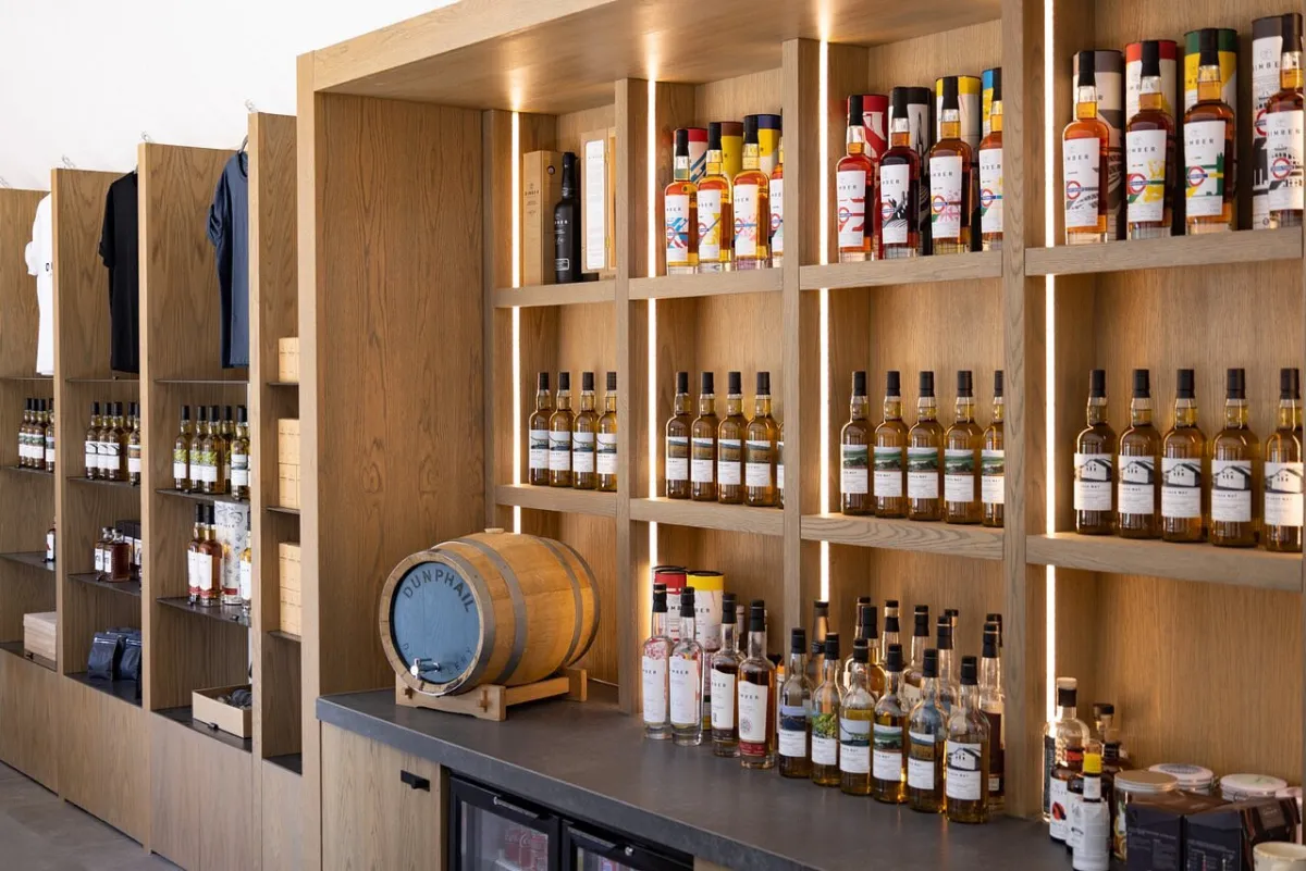 Shelves with bottles of whiskey and a small barrel.