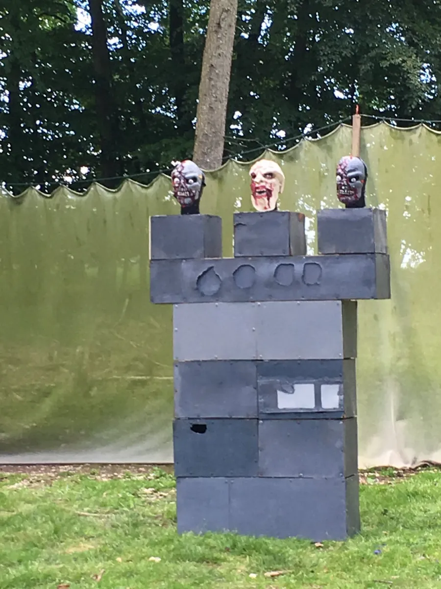 Three zombie heads on a block structure outdoors.