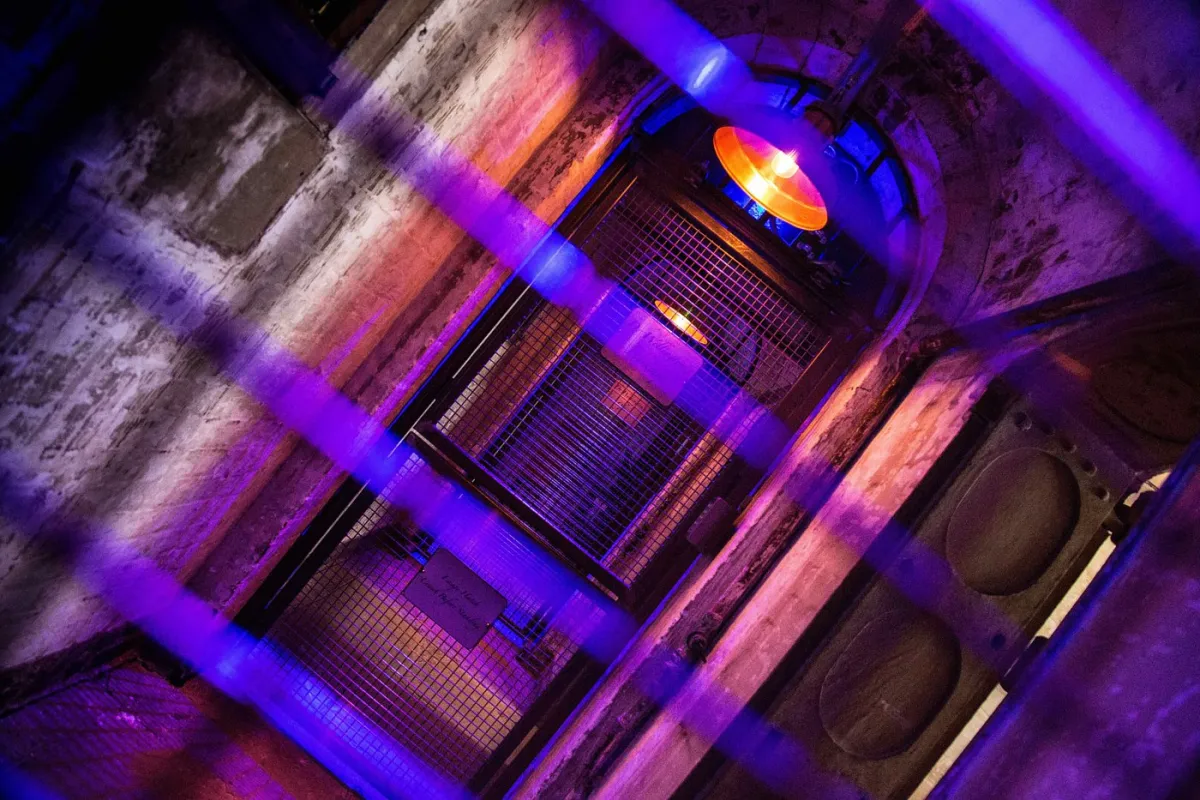 Dimly lit industrial hallway with purple and orange lights.