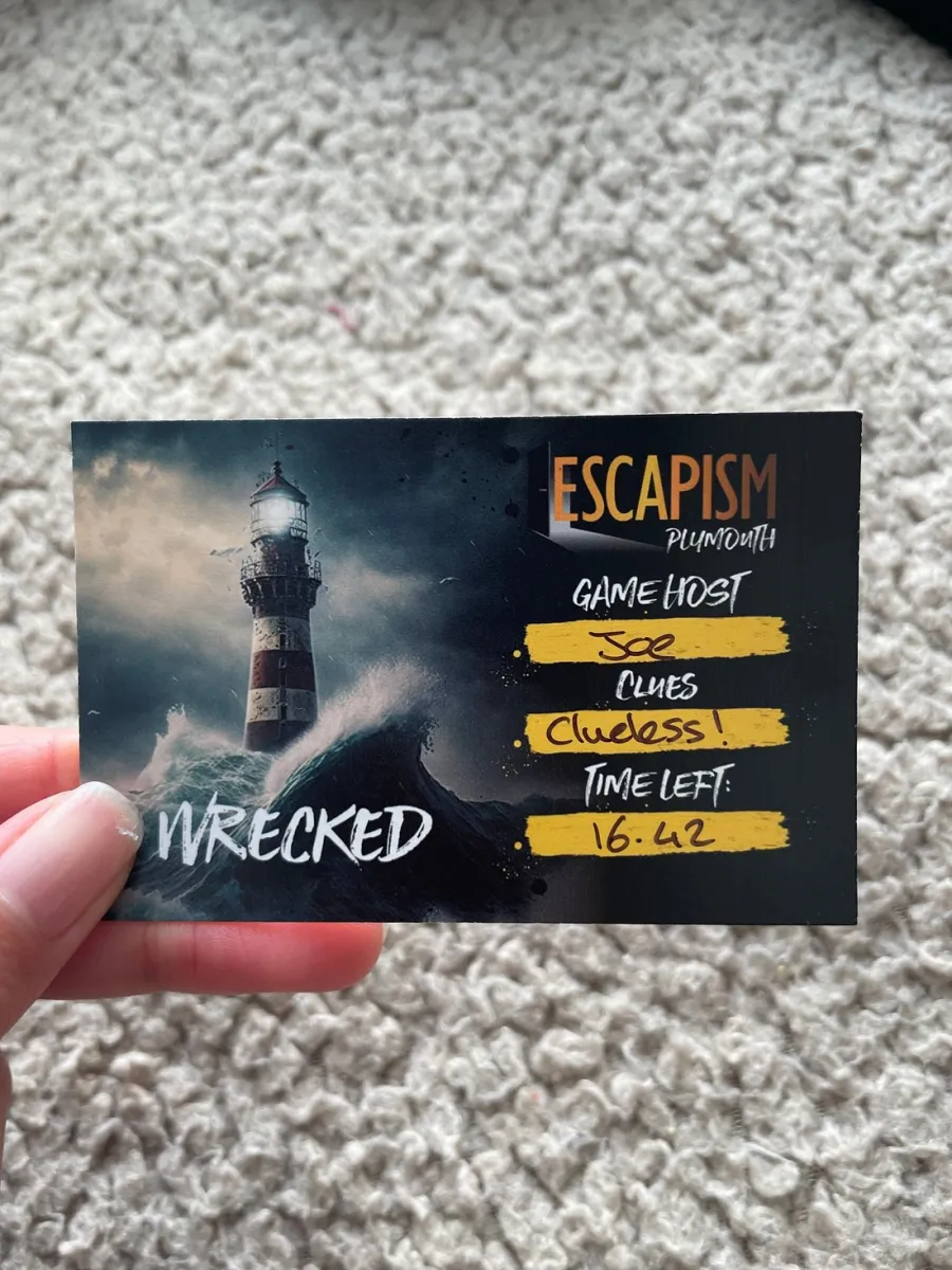 Hand holding a card with a lighthouse and game details.