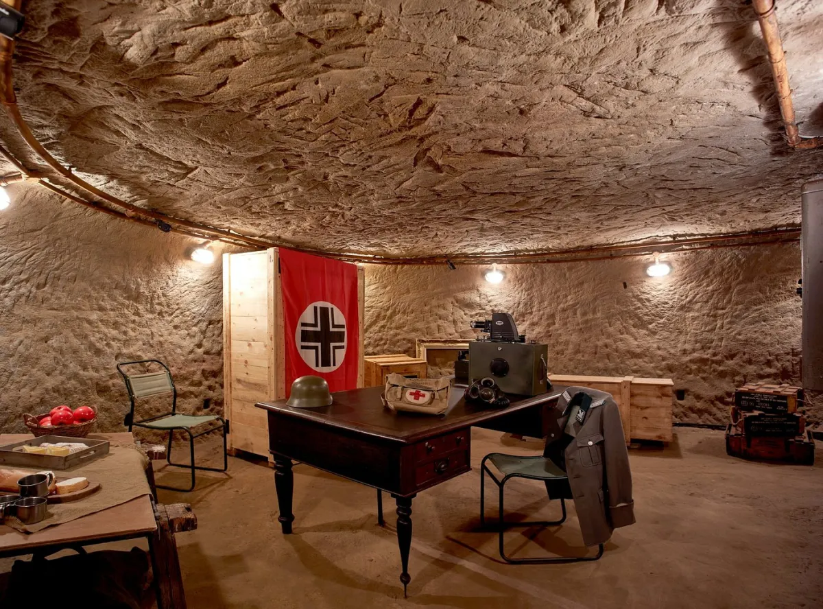 Underground bunker with desk, flag, and military items.
