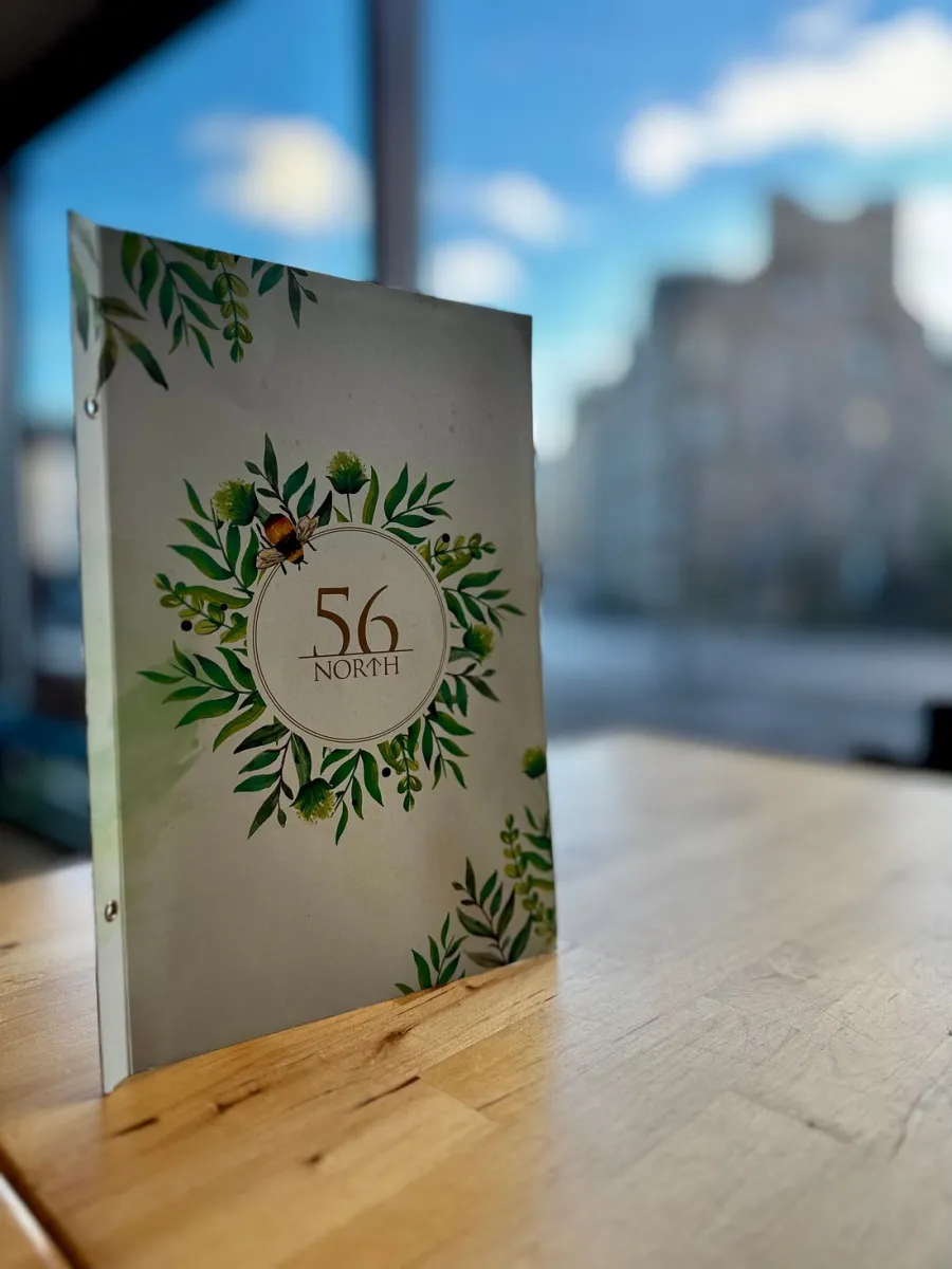 Menu standing on a wooden table with a floral design.