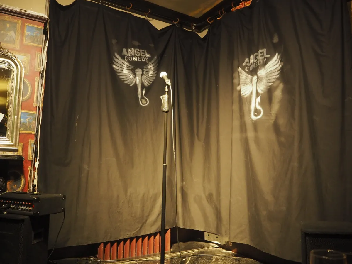 Empty comedy stage with microphone and black curtains.