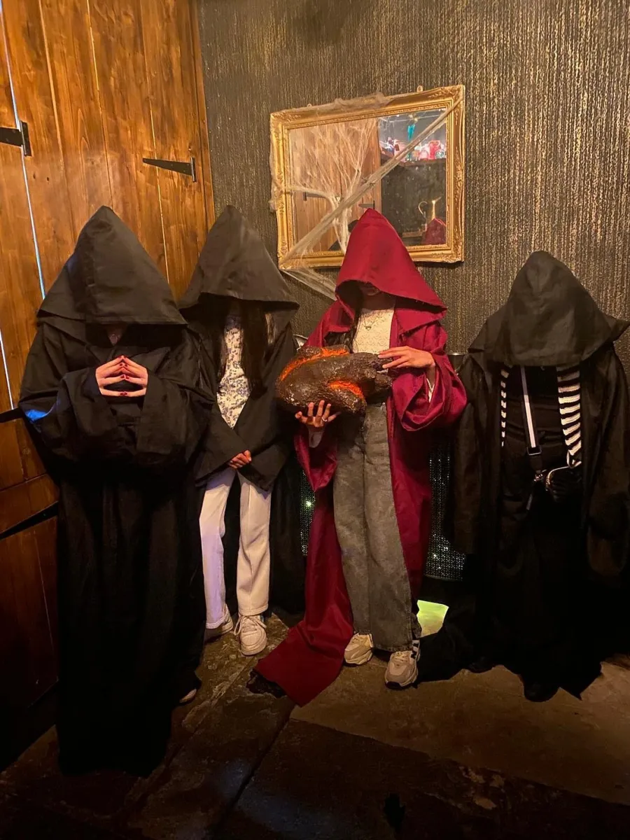 Four people in hooded robes, one holding a large object.