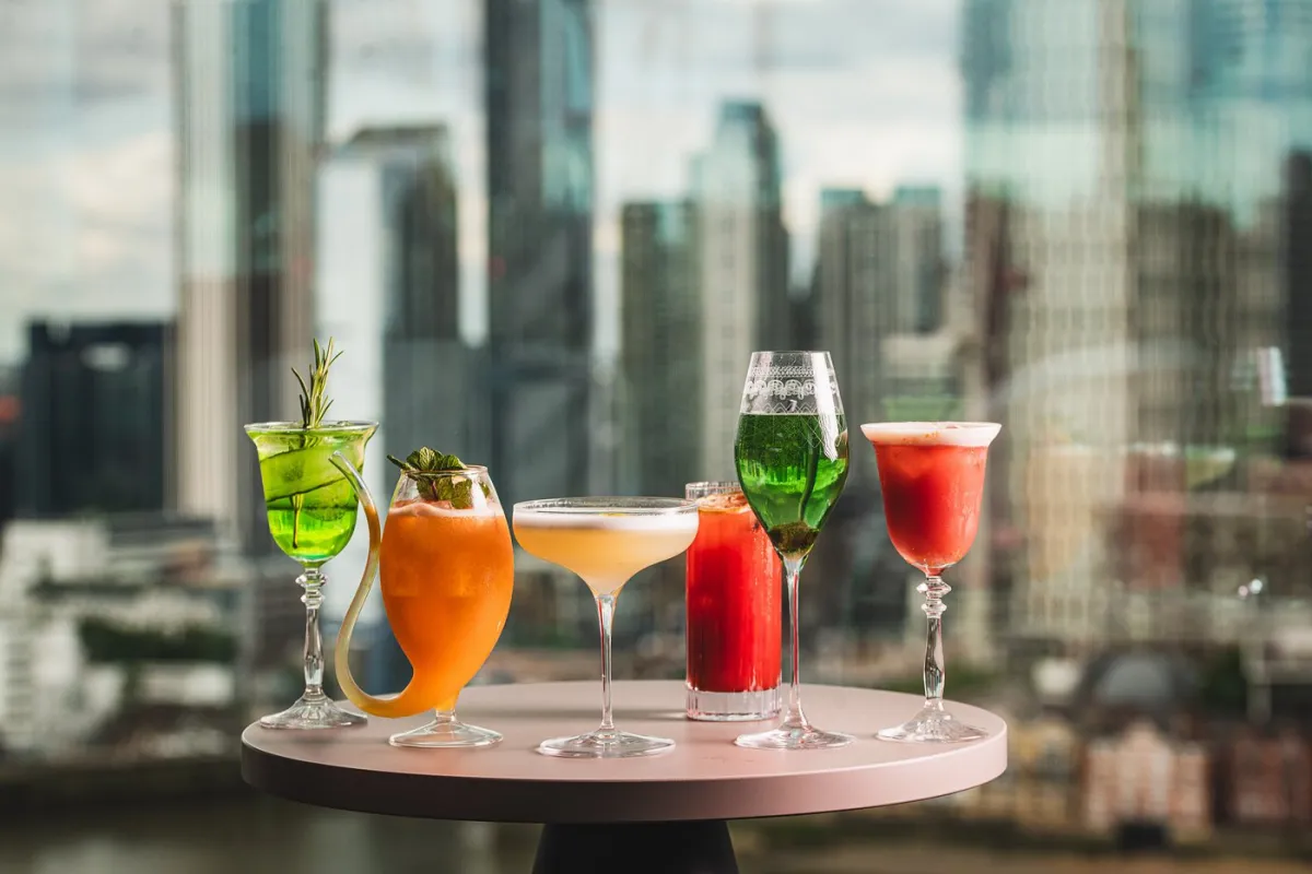 Assorted cocktails on a table with city skyline.