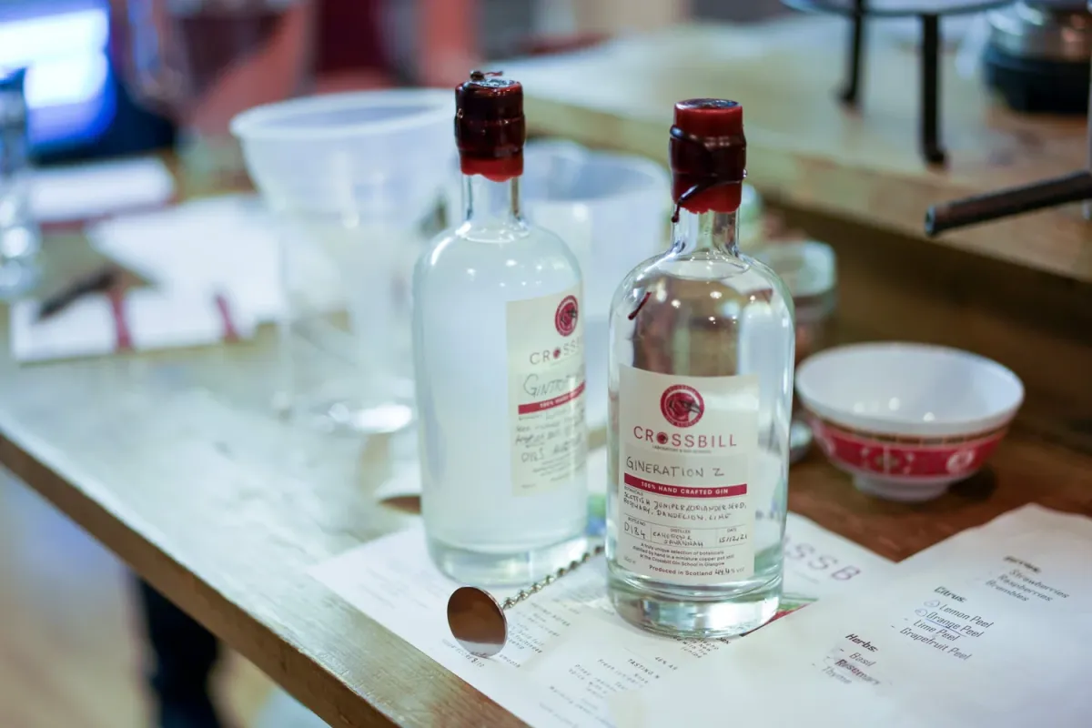 Two Crossbill gin bottles on a wooden table.