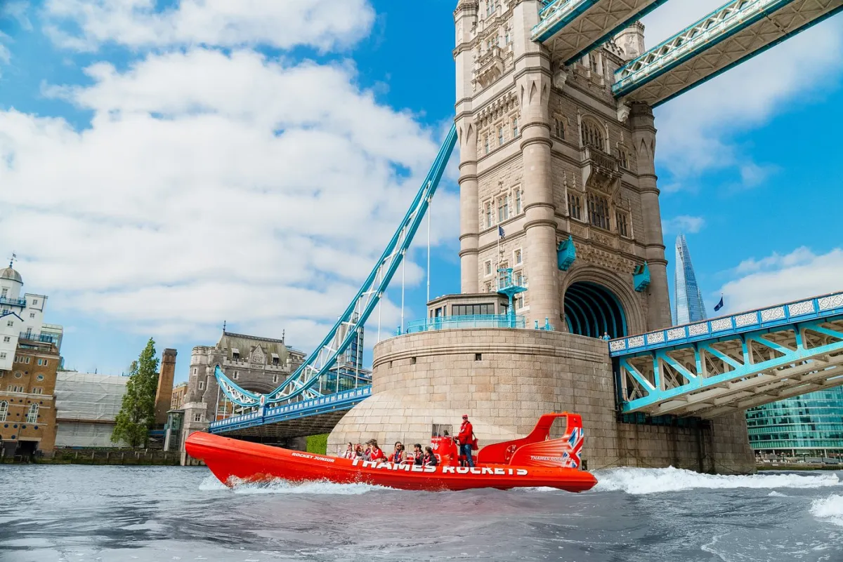 Red speedboat passing under Tower Bridge in London