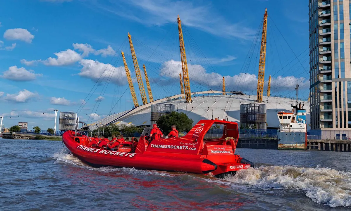 Red speedboat on river near large dome structure.