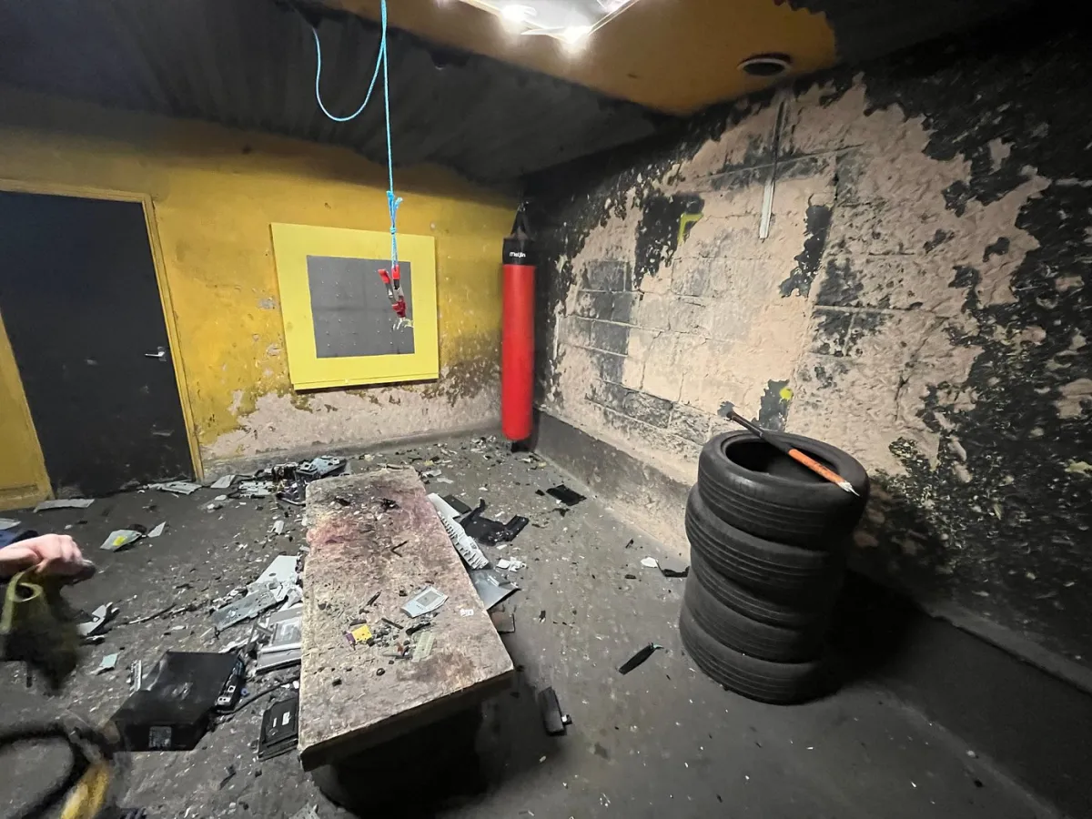 Room with damaged walls, debris, and a punching bag.