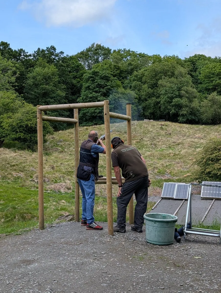 Two people target shooting in a wooded area.