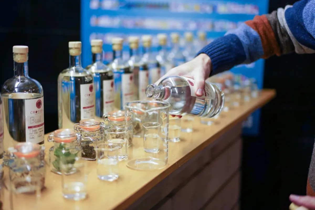 Person pouring liquid into a glass on a wooden counter.