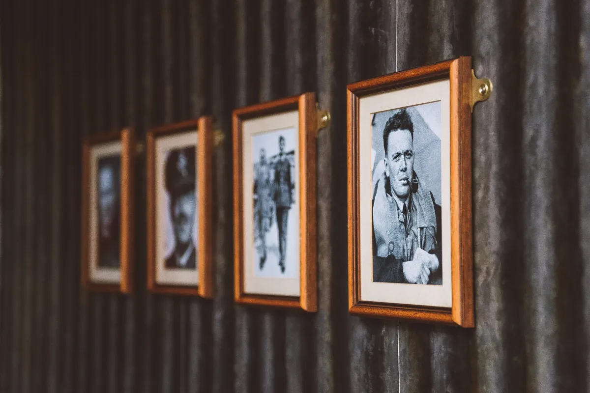 Framed black and white portraits on a corrugated wall.