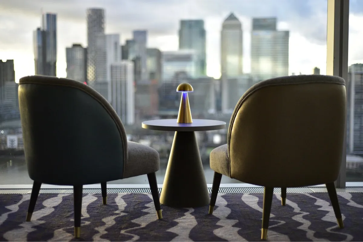 Two chairs and a table with a lamp, city skyline view.