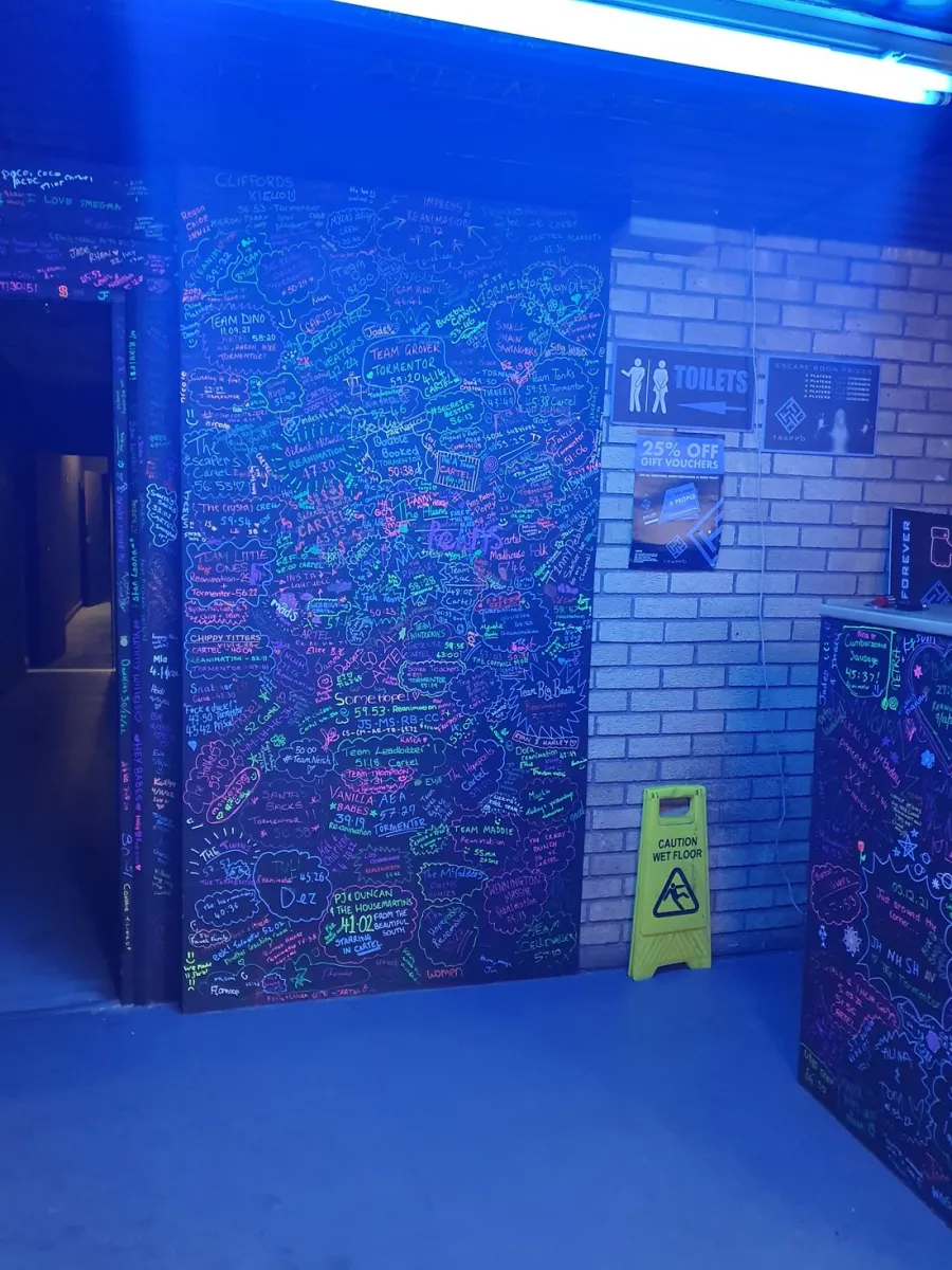 Wall with colorful graffiti and signs under blue light.