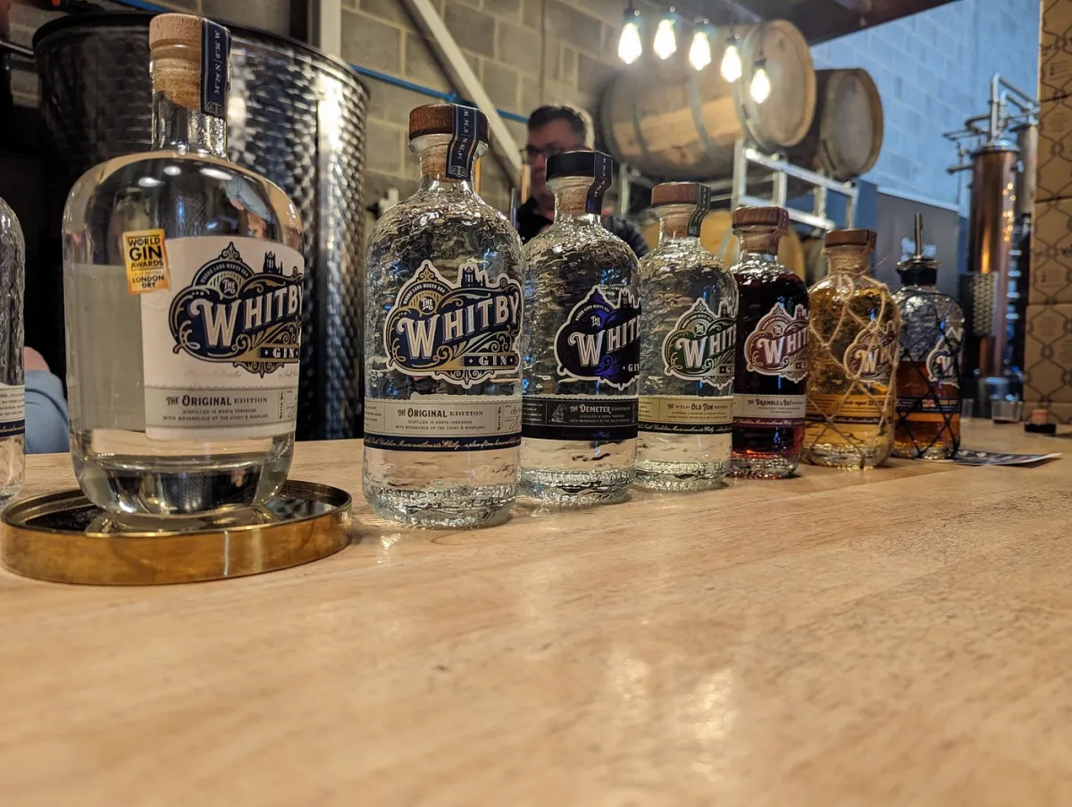 Row of Whitby gin bottles on a wooden table.