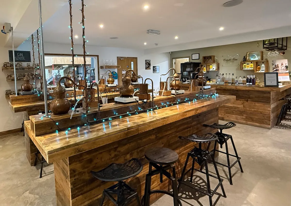 Interior of a gin distillery with copper stills and wooden counters.