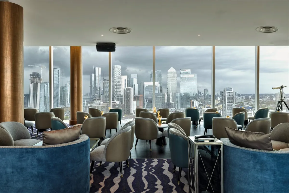 Modern lounge with city skyline view through large windows.