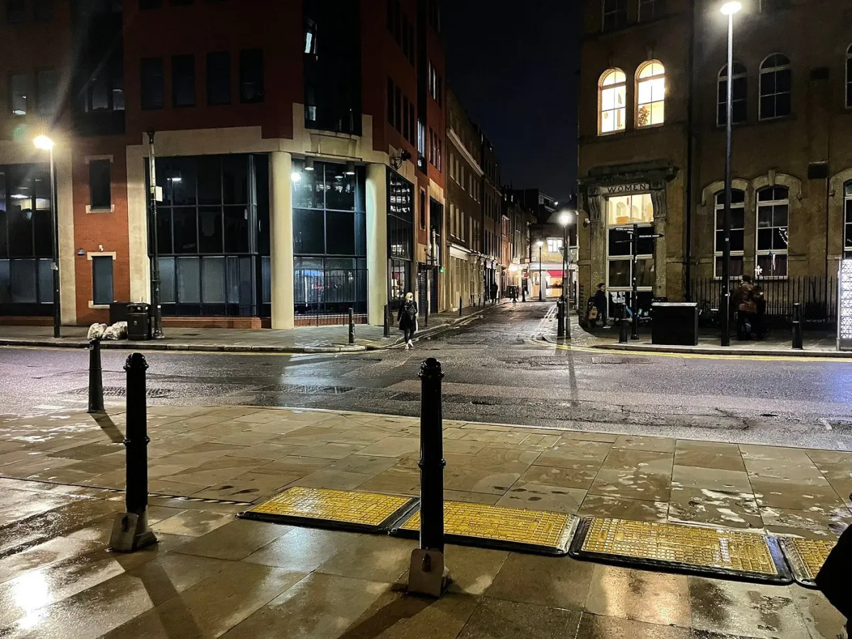 Empty city street at night with illuminated buildings.