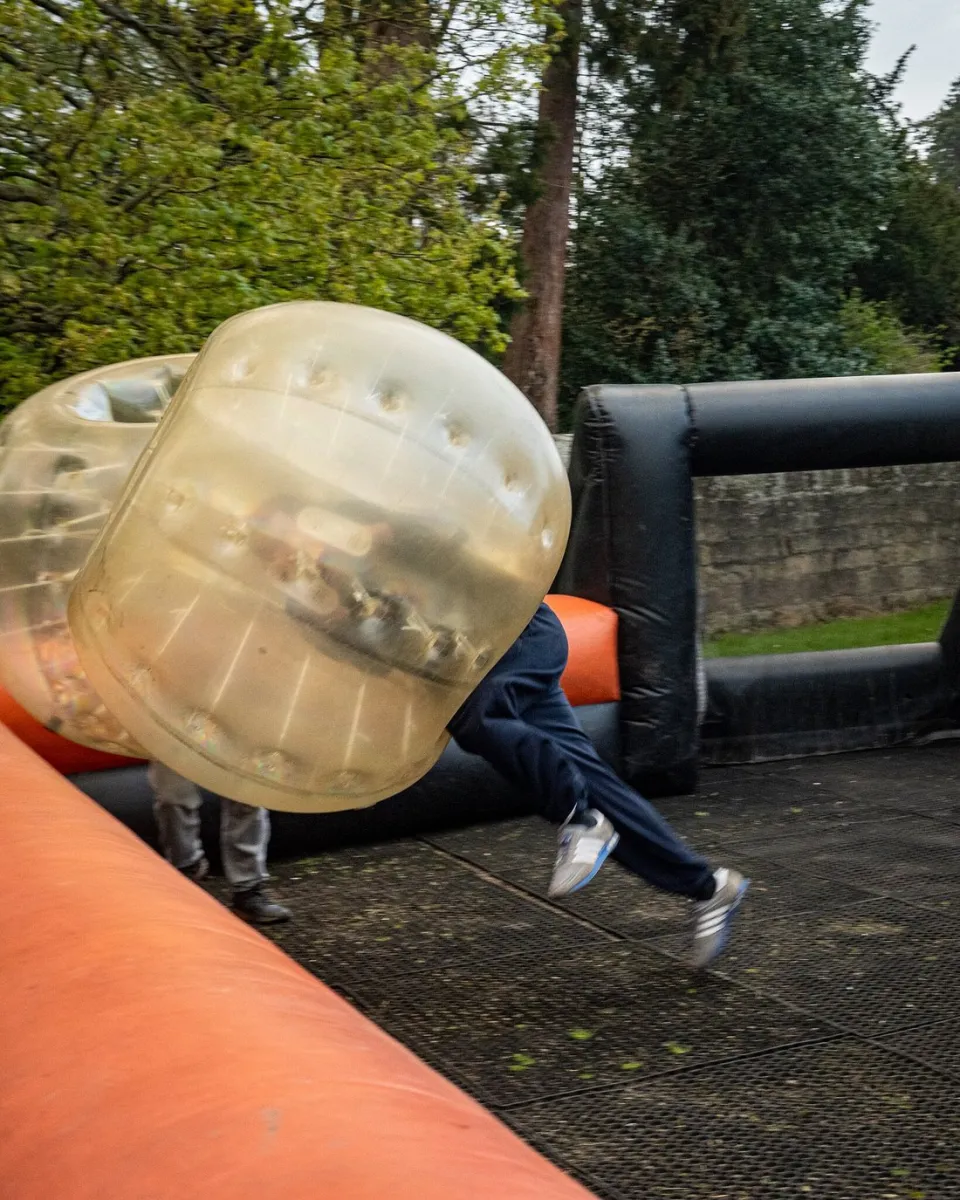 Person in a bubble suit running on an inflatable course.