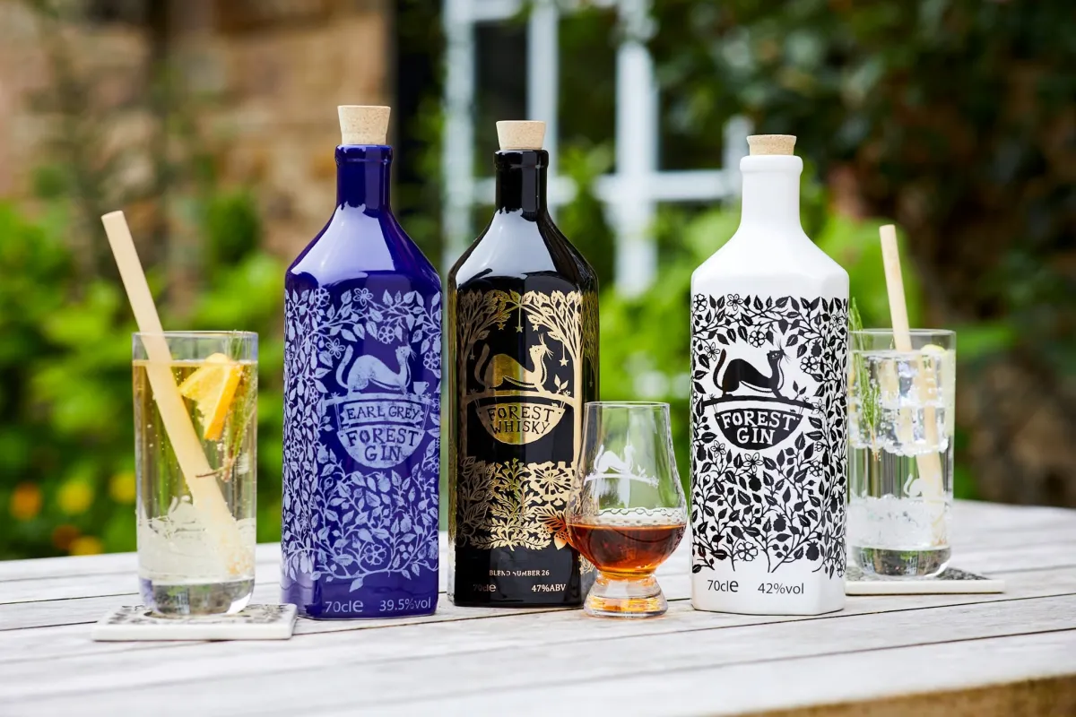 Bottles of Earl Grey Forest Gin, Forest Whisky, and Forest Gin on a table with glasses.