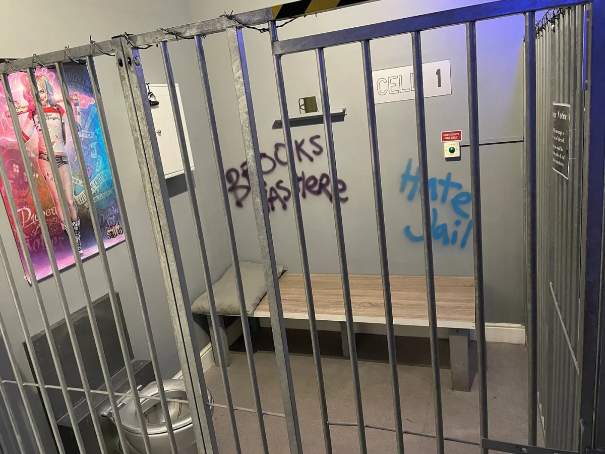 Graffiti-covered jail cell with a poster on the wall.